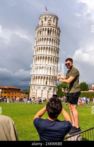 Un visitatore posa per le fotografie alla Torre Pendente di Pisa, il campo dei Miracoli, Pisa, Toscana, Italia. Foto Stock
