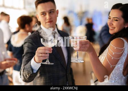 gli sposi novelli al banchetto versano champagne in una pila di bicchieri per gli ospiti Foto Stock