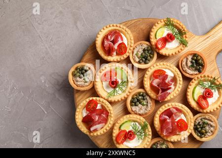 Stuzzichini deliziosi con jamon, pate e salsicce affumicate asciutte su un tavolo testurizzato grigio, vista dall'alto Foto Stock