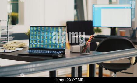 Ufficio con laptop che mostra gli elenchi di mercati azionari e mostra in background l'elenco dei clienti pianificati. Notebook con indici della piattaforma di trading e elenco delle consultazioni finanziarie dei clienti sul retro Foto Stock