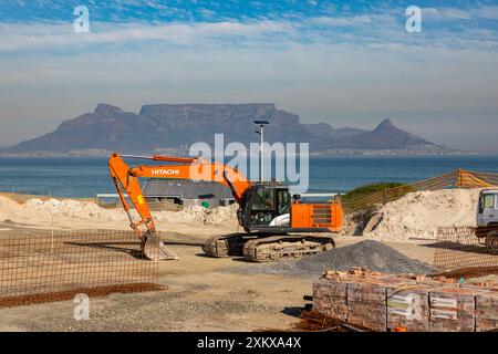 Cantiere vicino a una spiaggia di città del Capo con un escavatore Hitachi e vari altri materiali da costruzione che lo circondano. Foto Stock