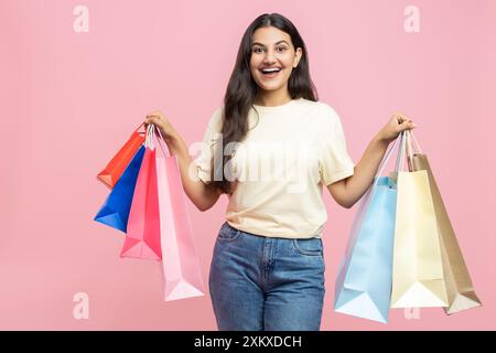 Donna eccitata che indossa T-shirt casual e jeans che tengono in mano le borse della spesa visitando una boutique alla moda Foto Stock