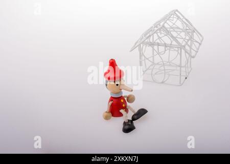 Pinocchio è seduto accanto a un modello di casa Foto Stock