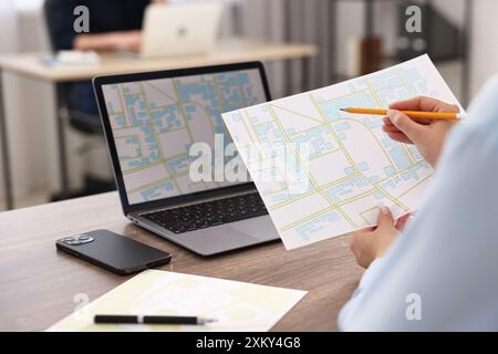 Cartografo che lavora con mappe catastali al tavolo di legno in ufficio, primo piano Foto Stock