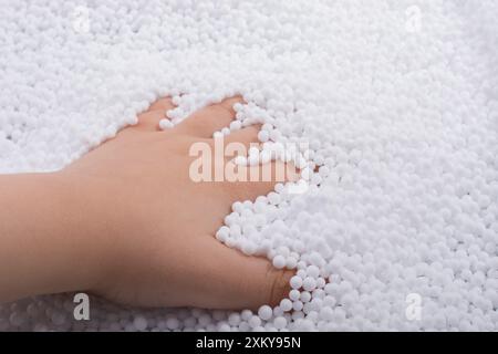 Bimbi in mano di polistirene bianco le sfere di schiuma come sfondo Foto Stock