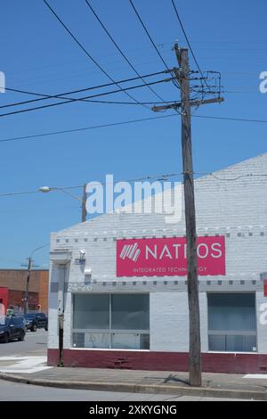 Parete bianca in mattoni, segno rosa, contro un cielo australiano azzurro, a sinistra un polo elettrico grigio asciutto attraversato da linee elettriche aeree Foto Stock