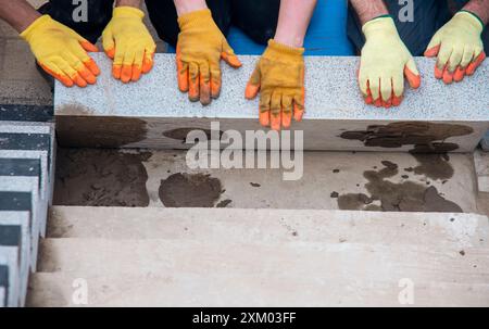 Passi concreti in costruzione come un team di costruttori installare blocchi di cemento pesanti Foto Stock