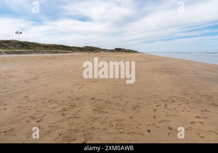 Le bandiere sventolano in cima alla cresta della duna sopra le ampie e vuote sabbie di Utah Beach, Normandia, Francia. Foto Stock