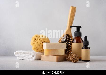 Pila di saponette organiche, pettine per capelli in bambù, biberon cosmetici, spugna naturale e asciugamano di cotone. Bagno e concetto di benessere. Foto Stock