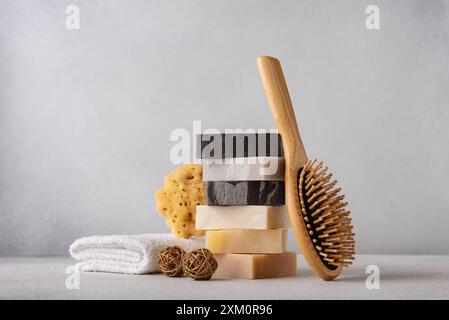 Pila di saponette organiche, pettine per capelli in bambù, spugna naturale e asciugamano di cotone. Bagno e concetto di benessere. Foto Stock