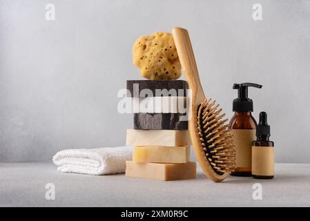 Pila di saponette organiche, pettine per capelli in bambù, biberon cosmetici, spugna naturale e asciugamano di cotone. Bagno e concetto di benessere. Foto Stock