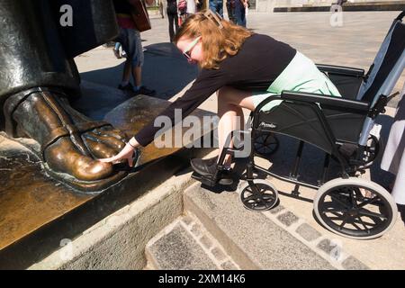 Toccando l'alluce a piedi, per fortuna, ragazza in sedia a rotelle / bambino disabili con statua del croato Gregorio di Nin 'Grgur Ninski' ex vescovo di Nin, Spalato Croazia. (138) Foto Stock