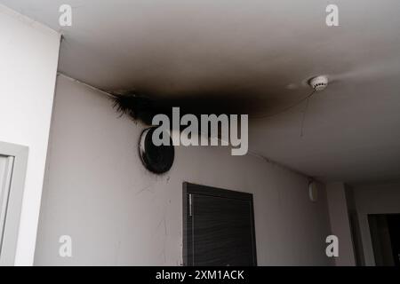 Lampada LED bruciata. Una lampada a paralume sulla parete dopo un incendio. Combustione spontanea e incendio in un edificio residenziale. Sensore di allarme antincendio interno Foto Stock