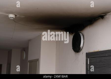 Lampada LED bruciata. Una lampada a paralume sulla parete dopo un incendio. Combustione spontanea e incendio in un edificio residenziale. Sensore di allarme antincendio in ambienti chiusi Foto Stock