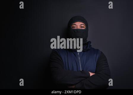 Uomo, ritratto e maschera del rapinatore in studio, ladro e criminale o sfondo nero per ladro. Uomo, balaclava e travestimento per cattivo Foto Stock
