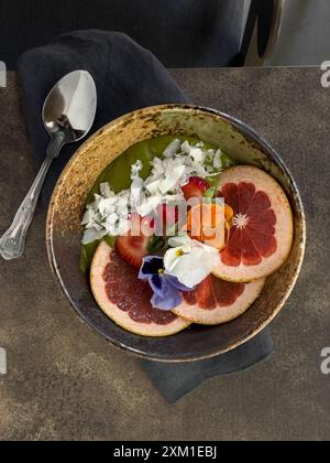 Ciotola per frullati Matcha con scaglie di arancia, fragola e cocco, splendidamente decorata. Foto Stock