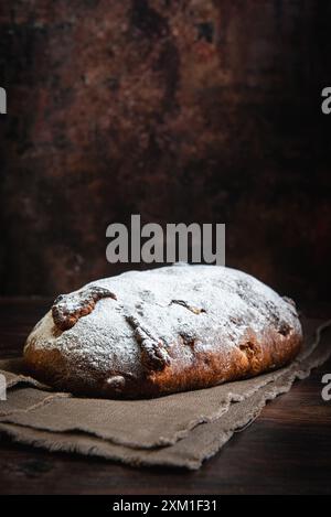 Pane a pasta madre fresca con frutta e noci su un tagliere. Foto Stock