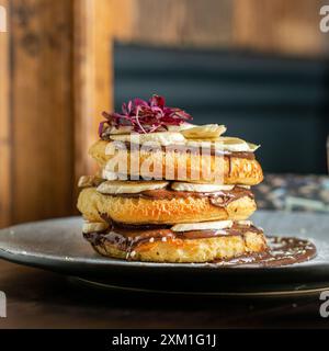 Soffici pancake alla banana fatti in casa con cioccolato su un tavolo del bar. Foto Stock