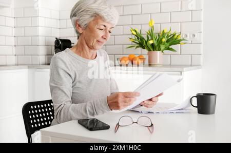 Allegra signora anziana che rivede l'accordo a casa Foto Stock