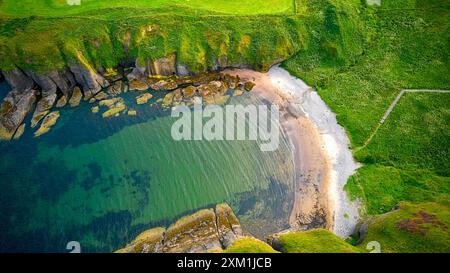 Cullykhan Beach Aberdeenshire Scozia piccola spiaggia di sabbia blu mare verde circondato da formazioni rocciose Foto Stock