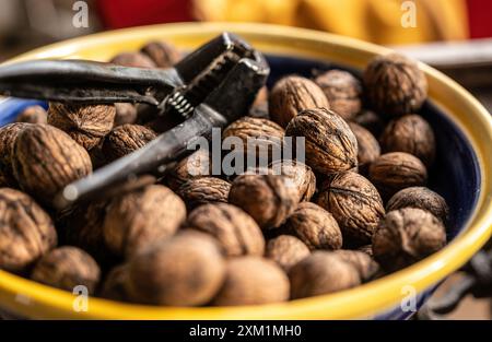 Noci e schiaccianoci nel primo piano del recipiente. Deliziose noci per una dieta vegetariana Foto Stock