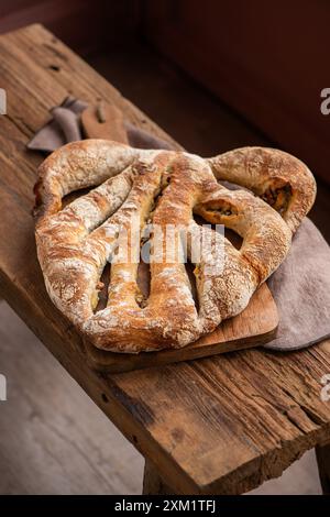 Formaggio a pasta madre e pane alle olive. Pane di frumento biologico appena sfornato su un tagliere su un banco di legno, con tovaglia di lino. Vista dall'alto Foto Stock