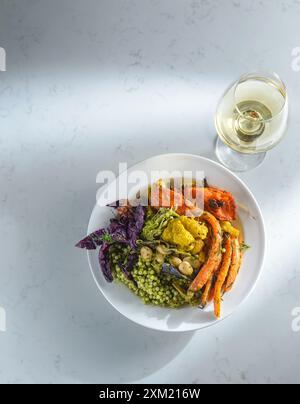 Vista dall'alto di una ciotola preparata con una varietà di verdure, verdure e fagioli su un tavolo bianco. Cibo sano. Vegetariano, cibo vegetariano. Foto Stock