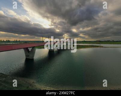 A picturesque sunset over the Hanseatic Arch in Zwolle, the Netherlands. The dramatic sky, filled with menacing clouds, creates a mesmerizing scene.  Foto Stock