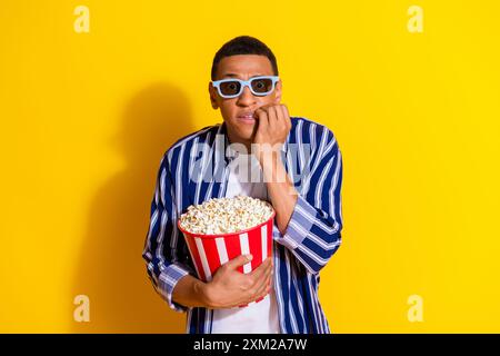 Foto di un uomo terrorizzato con un'elegante camicia vestita di capelli in occhiali 3d mangia popcorn guarda orrore isolato su uno sfondo dai colori vivaci Foto Stock