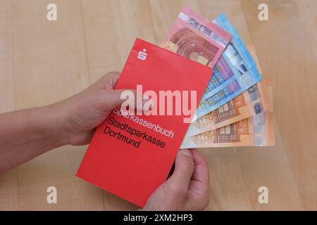 FrauenhŠnde halten ein Sparbuch der Sparkasse Dortmund in dem einige Euro Geldscheine Stecken *** mani femminili in mano a Sparkasse Dortmund Savings b Foto Stock