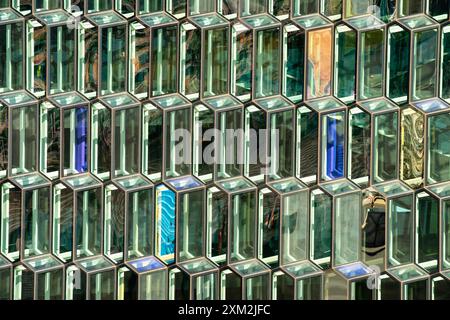 Finestre in vetro geometrico astratto che riflettono la luce del sole sulla facciata dell'edificio moderno Foto Stock