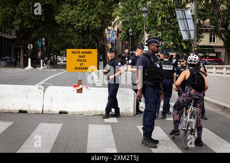 Parigi, Francia. 23 luglio 2024. Gli agenti di polizia sorvegliano un punto d'ingresso al perimetro di sicurezza durante i preparativi per le Olimpiadi di Parigi. Pochi giorni prima dell'inaugurazione senza precedenti dei Giochi Olimpici di Parigi, che si svolgeranno lungo i 6 chilometri della Senna, la città della luce è in fase di metamorfosi. Le ringhiere sono state erette intorno al perimetro molto ristretto dell'area dove si svolgerà la cerimonia di apertura, in modo da poter vedere strade completamente vuote, così come le terrazze di caffè e ristoranti. Credito: SOPA Images Limited/Alamy Live News Foto Stock