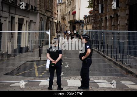 Parigi, Francia. 23 luglio 2024. Gli agenti di polizia sorvegliano un punto d'ingresso al perimetro di sicurezza durante i preparativi per le Olimpiadi di Parigi. Pochi giorni prima dell'inaugurazione senza precedenti dei Giochi Olimpici di Parigi, che si svolgeranno lungo i 6 chilometri della Senna, la città della luce è in fase di metamorfosi. Le ringhiere sono state erette intorno al perimetro molto ristretto dell'area dove si svolgerà la cerimonia di apertura, in modo da poter vedere strade completamente vuote, così come le terrazze di caffè e ristoranti. Credito: SOPA Images Limited/Alamy Live News Foto Stock