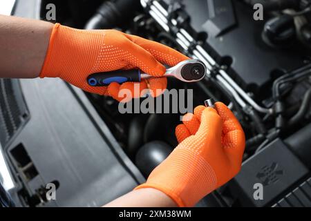 Meccanico automatico con chiave dinamometrica che fissa l'auto presso l'officina di riparazione di automobili, primo piano Foto Stock