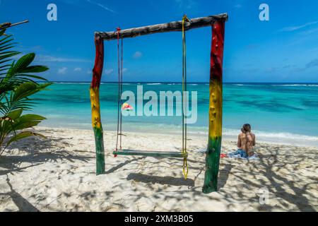 Donna seduta vicino a un'altalena colorata sulla scenografica spiaggia di sabbia tropicale Anse Source d'Argent, l'isola di la Digue, Seychelles Foto Stock