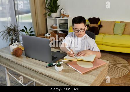 Un ragazzo con la sindrome di Down siede a una scrivania in casa sua, concentrandosi sui suoi studi. Foto Stock