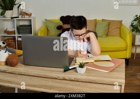 Un ragazzo con la sindrome di Down si siede a un tavolo per studiare. Foto Stock