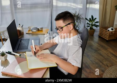 Un ragazzo con la sindrome di Down siede alla sua scrivania, concentrandosi sul disegno. Foto Stock