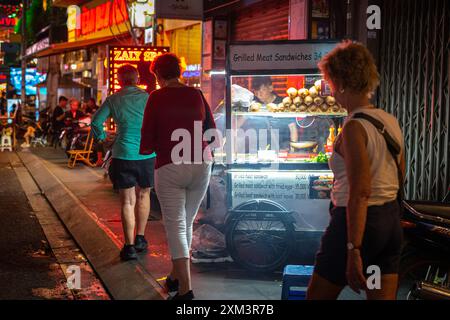 Ho chi Minh City, Vietnam - 26 maggio 2024: I viaggiatori passano davanti a un banco di panini di notte in bui Vien Street. Foto Stock