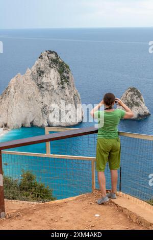 giovane donna in vacanza sull'isola greca di zante o zante, ammirando le rocce e le scogliere sulla costa con binocoli Foto Stock