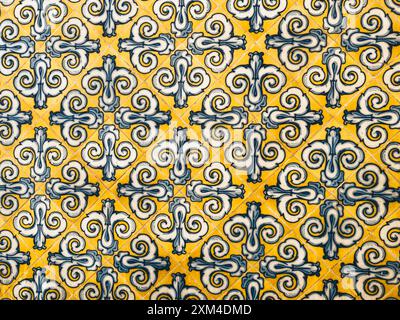 Primo piano di piastrelle decorative caratterizzate da un motivo geometrico blu e giallo, che mette in risalto il design intricato e la maestria artigianale delle piastrelle tradizionali. Foto Stock