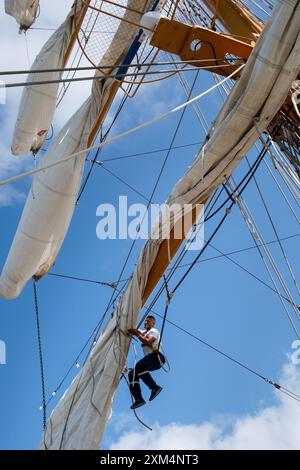 MARIEHAMN, Åland, FINLANDIA - LUGLIO 25 2024: I marinai salgono in alto nel cielo per lavorare sulle vele sugli alberi del sommergibile Guayas dall'Ecuador. Secondo giorno della terza tappa Åland della corsa delle navi alte 2024 nel porto principale, Mariehamn, Åland, Finlandia. Foto: Rob Watkins/Alamy Live News. INFO: La Tall Ships Race è un evento velico annuale che comprende navi d'alto livello storiche e moderne. Promuove l'amicizia internazionale e la formazione dei giovani, attirando partecipanti e spettatori in tutto il mondo per celebrare il patrimonio marittimo e l'arte della vela tradizionale. Foto Stock