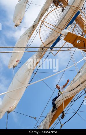 MARIEHAMN, Åland, FINLANDIA - LUGLIO 25 2024: I marinai salgono in alto nel cielo per lavorare sulle vele sugli alberi del sommergibile Guayas dall'Ecuador. Secondo giorno della terza tappa Åland della corsa delle navi alte 2024 nel porto principale, Mariehamn, Åland, Finlandia. Foto: Rob Watkins/Alamy Live News. INFO: La Tall Ships Race è un evento velico annuale che comprende navi d'alto livello storiche e moderne. Promuove l'amicizia internazionale e la formazione dei giovani, attirando partecipanti e spettatori in tutto il mondo per celebrare il patrimonio marittimo e l'arte della vela tradizionale. Foto Stock