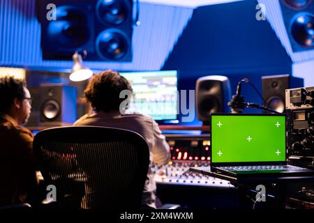 Artista e tecnico elaborano nuovi suoni in studio professionale e utilizzano la console audio per modificare i brani. Team di musicisti che producono un nuovo album e creano musica, premendo pulsanti e switcher. Foto Stock