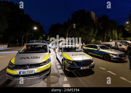 Amburgo, Germania. 25 luglio 2024. Gli agenti di polizia stanno in piedi su una strada durante un'operazione nel quartiere di Amburgo di Lurup. Un uomo apparentemente instabile mentalmente ha innescato un'importante operazione di polizia ad Amburgo-Lurup. Credito: Bodo Marks/dpa/Alamy Live News Foto Stock