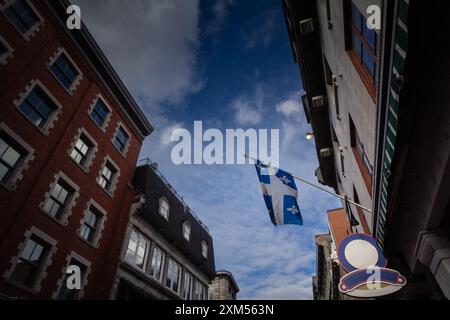 Foto di una bandiera del Quebec che sventola in aria a montreal, di fronte a un cielo blu. La bandiera del Québec, chiamata Fleurdelise, fu adottata per il provi Foto Stock