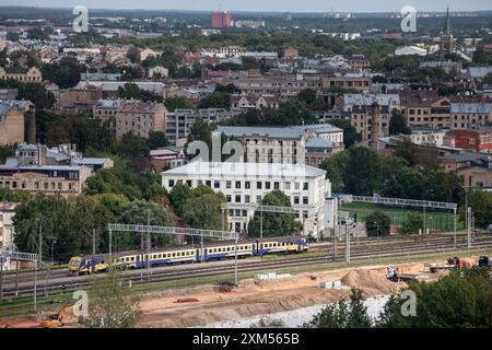 Panorama aereo di riga, Lettonia, con particolare attenzione a un treno lettone che viaggia lungo i binari ferroviari. Questa immagine cattura la rete di trasporto della città Foto Stock