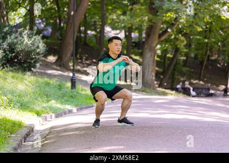 Asiatico giovane uomo corridore sportivo allenatore atletico maschile in buona forma fisica facendo esercizi di sport mattutino di riscaldamento, yoga ginnastica stretching muscoli evitare tensione corporea stile di vita sano nel parco. Foto Stock