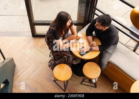 Vista dall'alto di una giovane coppia seduta in un bar, gustando la birra e conversando. Creano un'atmosfera calda e rilassata in una Foto Stock