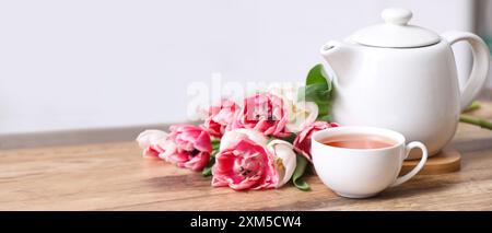 Teiera, tazza di bevanda calda e fiori sul tavolo. Banner per il design Foto Stock